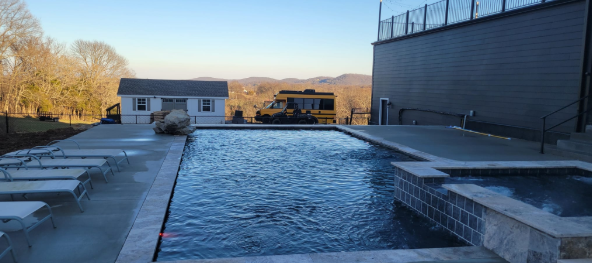 Luxury rectangular gunite pool with spa and travertine coping built by Pool Fever