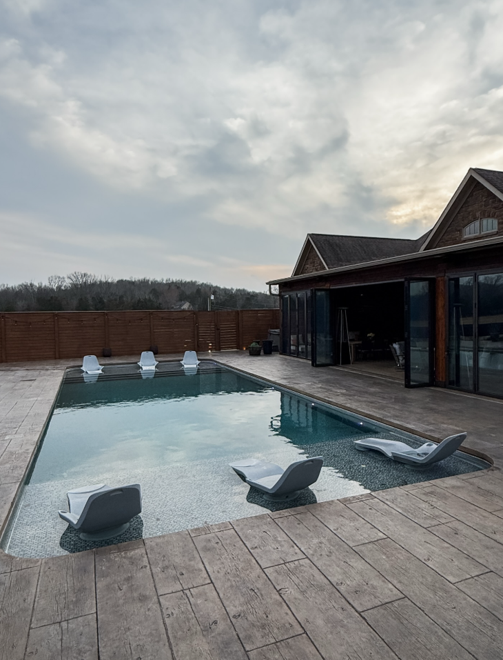 Luxury rectangular inground pool with travertine deck and lounge chairs in Middle Tennessee
